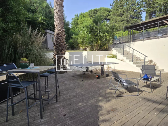 Wooden terrace with garden furniture and barbecue, surrounded by greenery.