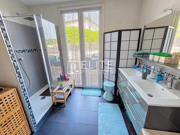 Modern bathroom with shower and double vanity unit, windows opening to the outside.
