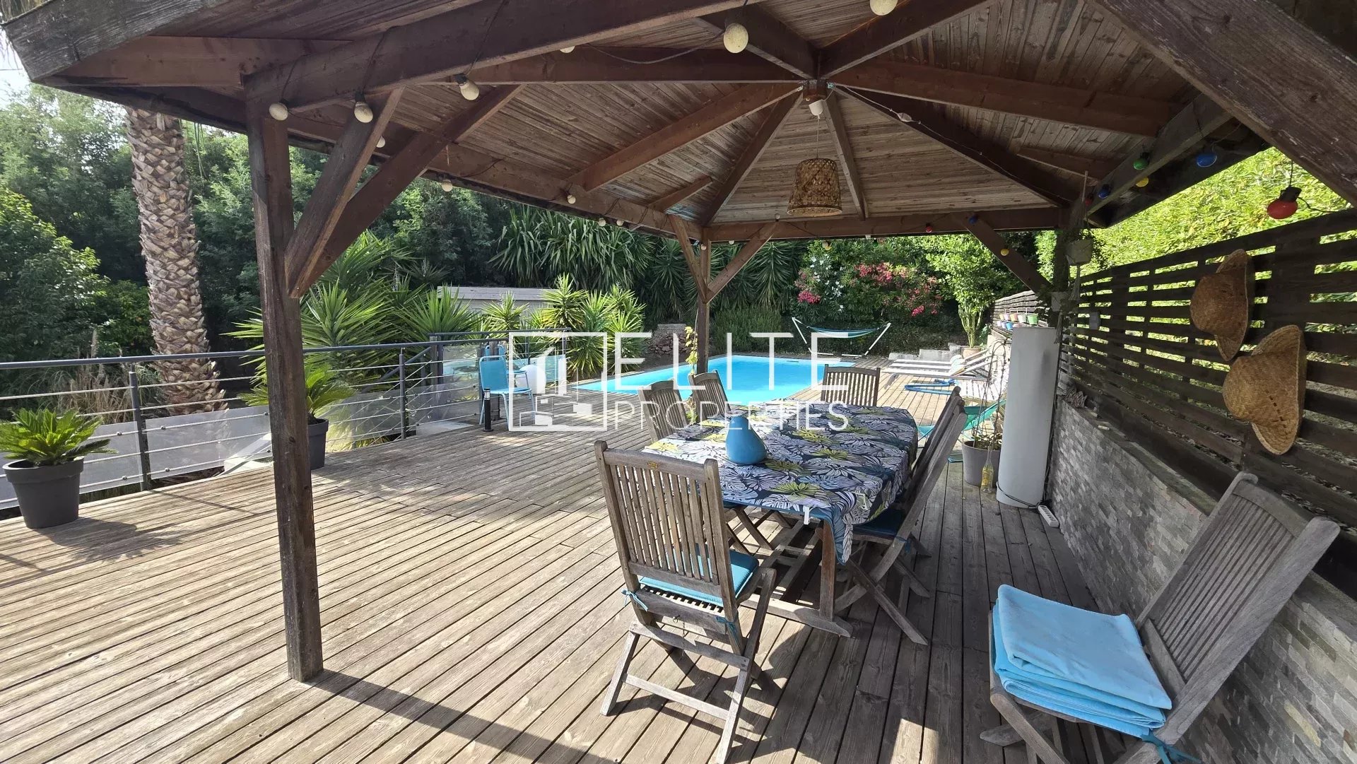 Terrace with swimming pool in Cannes Wooden terrace with garden furniture and swimming pool, surrounded by greenery.