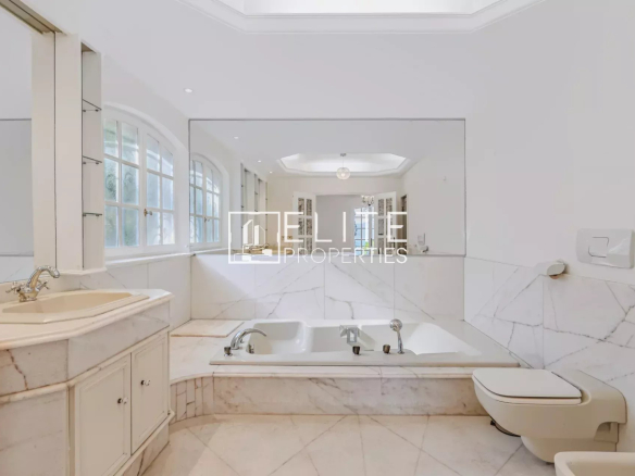Salle de bain spacieuse avec baignoire et miroir, murs en marbre blanc.