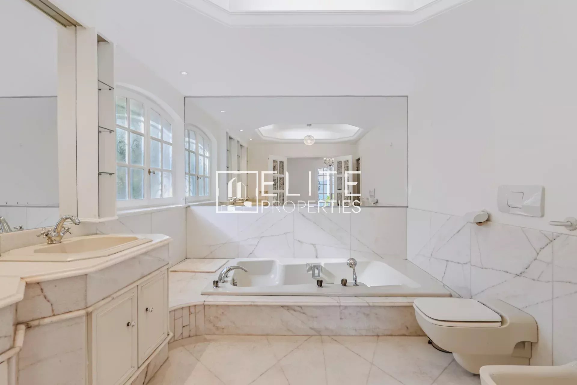 Salle de bain élégante Salle de bain spacieuse avec baignoire et miroir, murs en marbre blanc.
