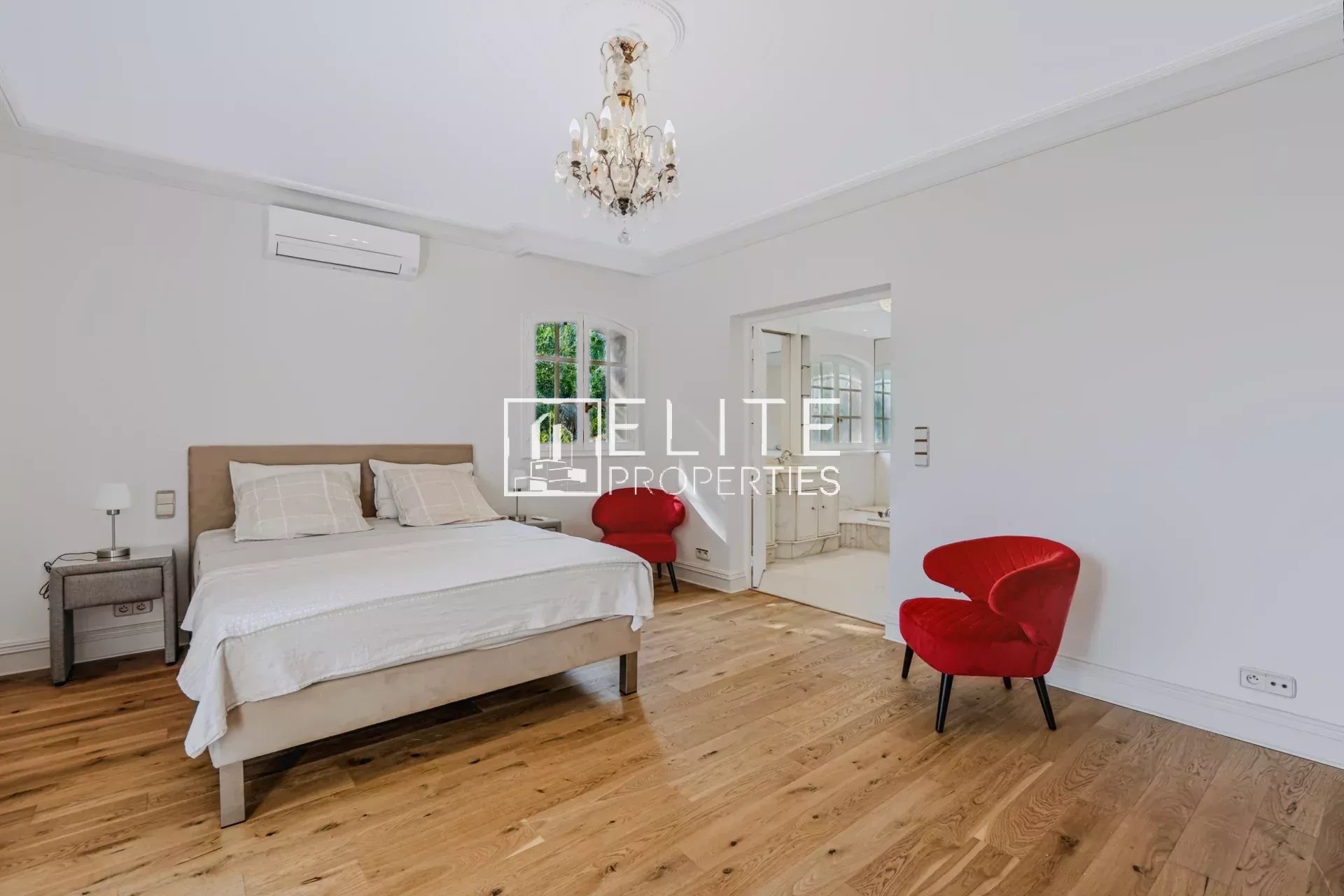Chambre élégante dans une maison de charme Chambre d'une maison de charme avec lit double et fauteuils rouges, parquet en bois.