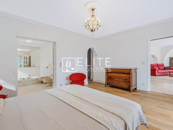 Chambre lumineuse avec mobilier en bois et accès à une salle de bain, maison de charme à Mandelieu-la-Napoule.