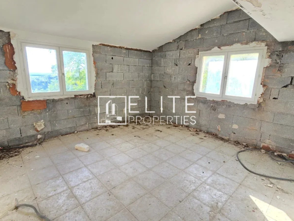 Intérieur d'une maison abandonnée à rénover, murs en parpaings, fenêtres avec vue sur la mer.