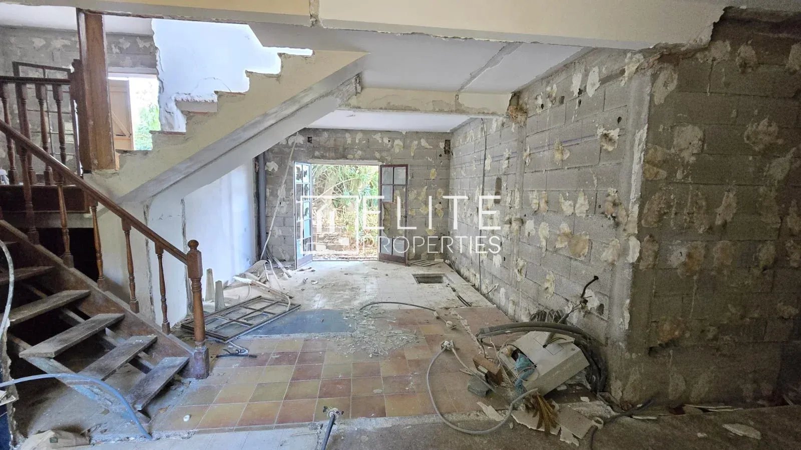Maison à rénover à Vallauris Intérieur d'une maison individuelle abandonnée à rénover, avec des murs en béton et un escalier en bois.