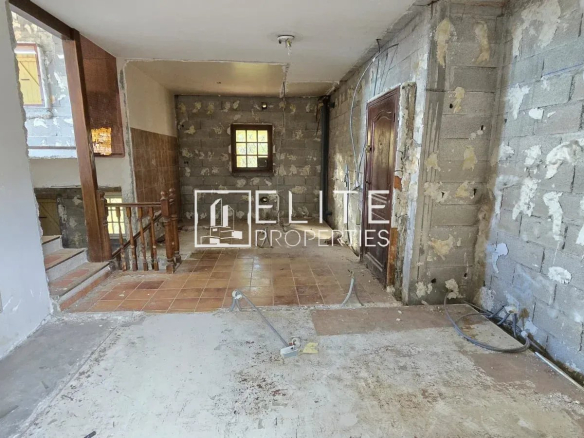 Intérieur d'une maison individuelle à rénover, murs en béton et carrelage au sol.