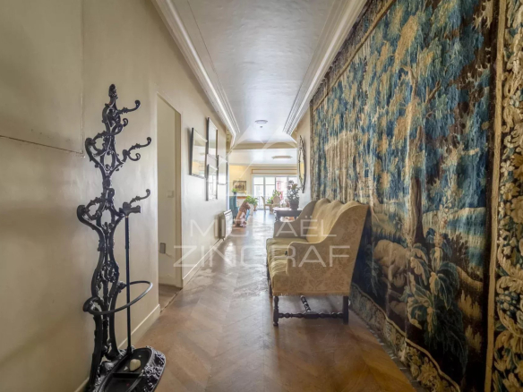 Intérieur d'un appartement avec un couloir décoré et un tapis mural, lumineux et spacieux.
