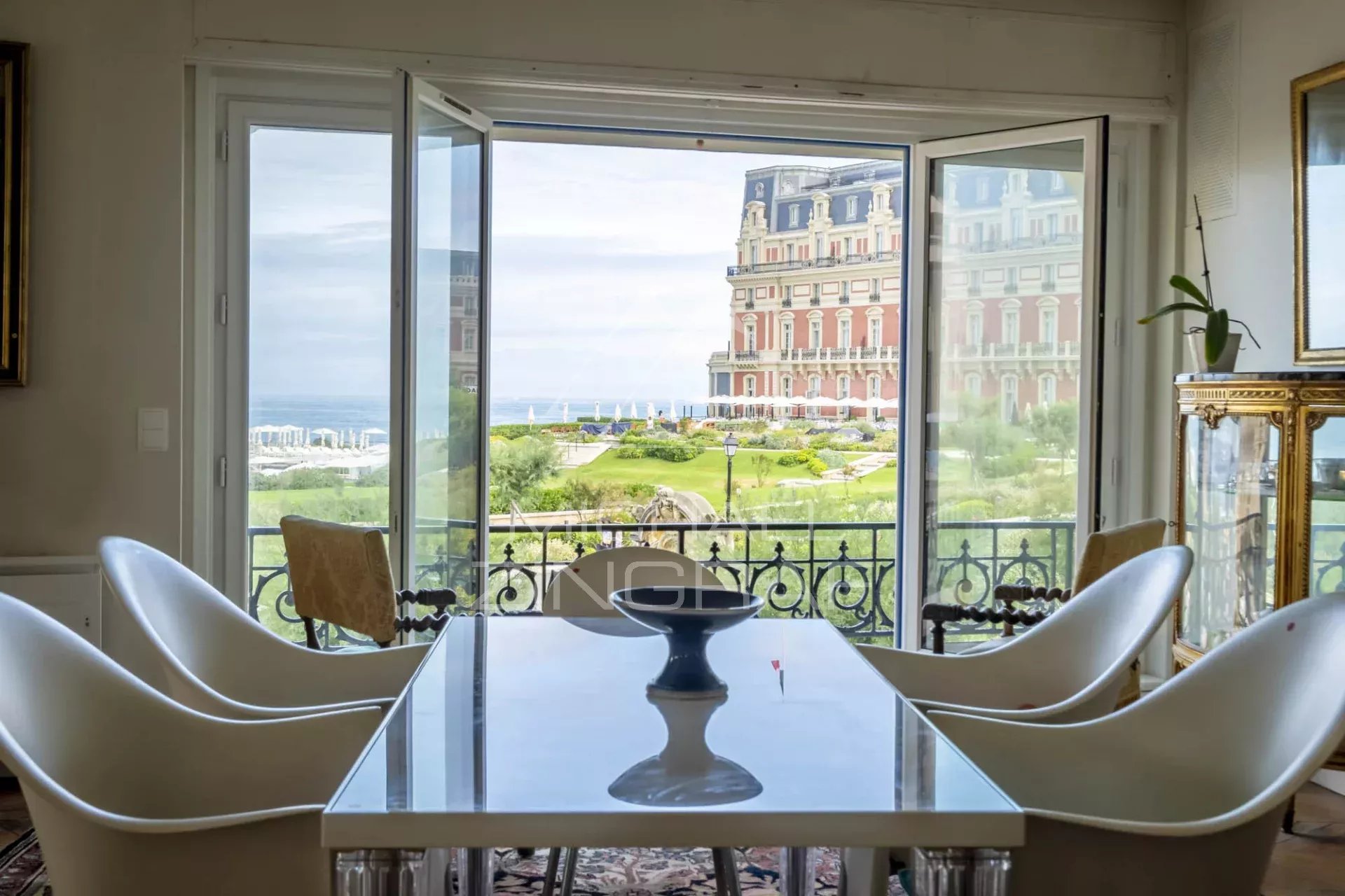 Appartement avec vue sur l’océan à Biarritz Vue depuis un appartement lumineux avec une table et des chaises, donnant sur l'océan et l'hôtel du Palais à Biarritz.