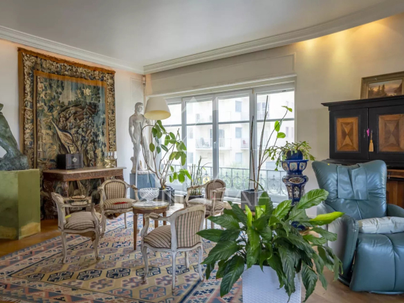 Salon lumineux d'un appartement avec vue sur l'océan, décoré de sculptures et plantes.
