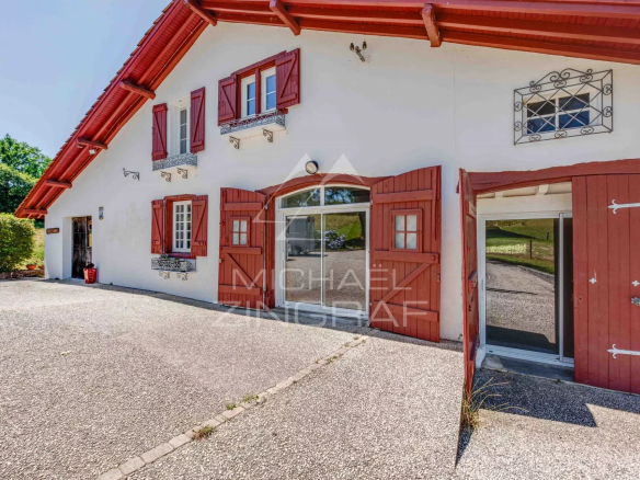 Renovated old farmhouse with red and white facade, surrounded by greenery.