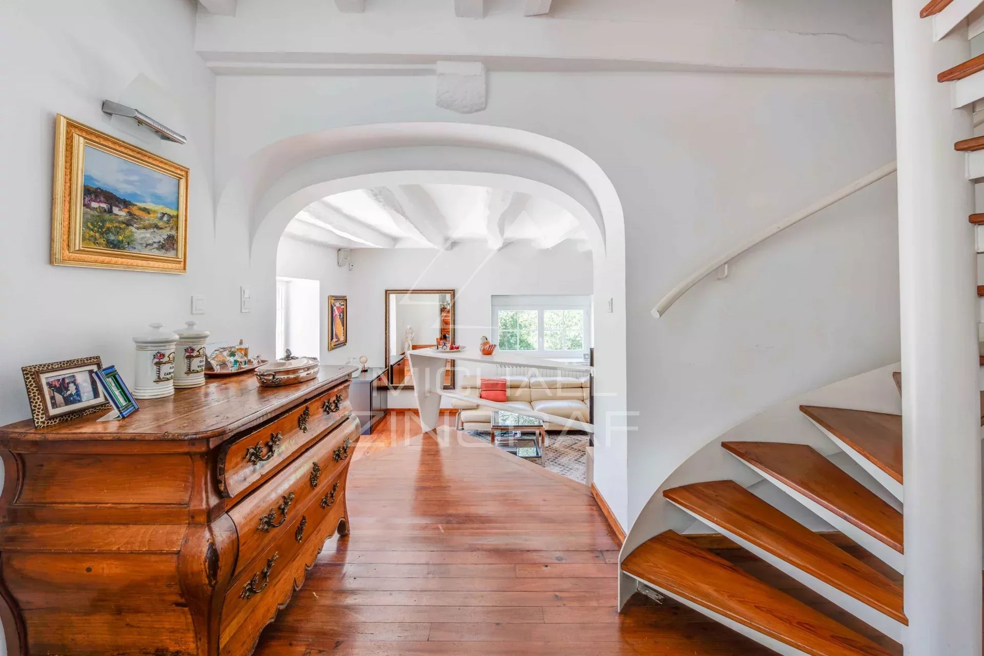 Interior of a renovated old farmhouse with a wooden staircase and white walls.