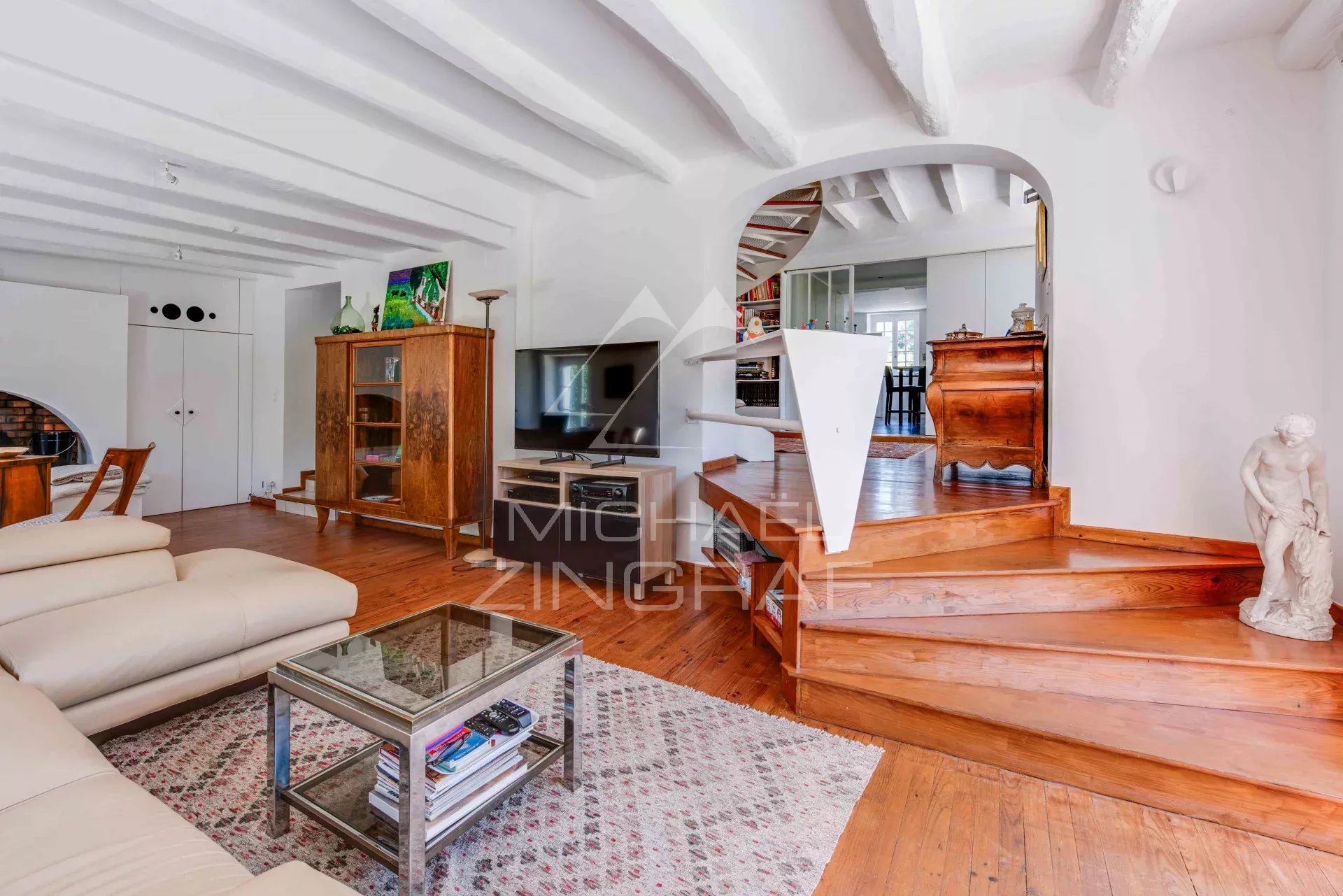 Interior of a renovated old farmhouse with living room and wooden staircase, modern and warm decor.