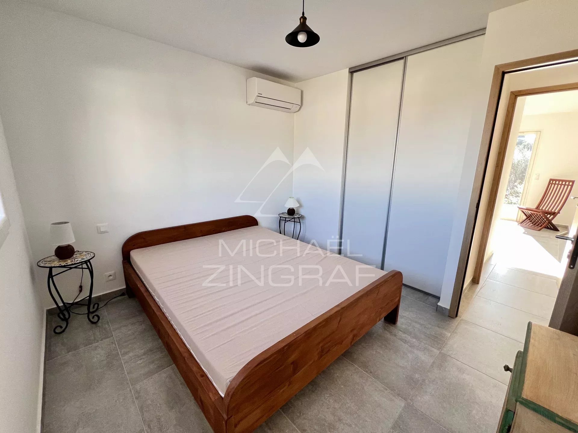 Villa room in Zonza Bedroom in a contemporary villa with a wooden bed and light-colored walls.