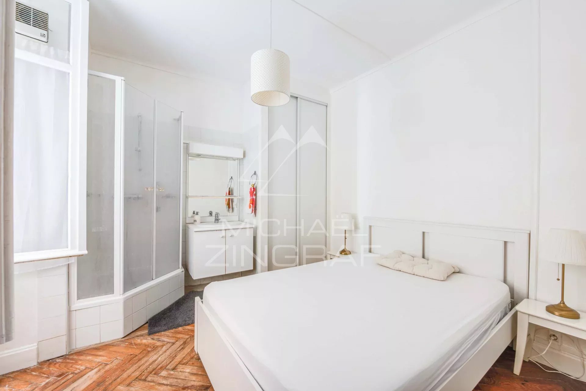 Chambre d'un appartement à Biarritz avec salle de bain attenante et décoration sobre.