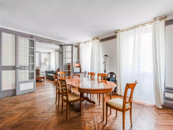 Intérieur d'un appartement spacieux avec un salon et une salle à manger, parquet en bois et lumière naturelle.