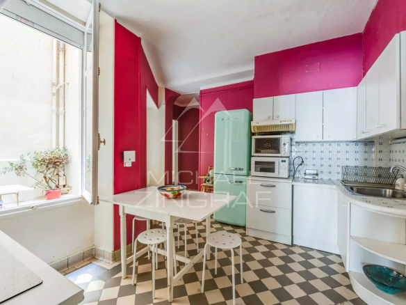 Cuisine moderne avec murs roses et carrelage noir et blanc dans un appartement à Biarritz.