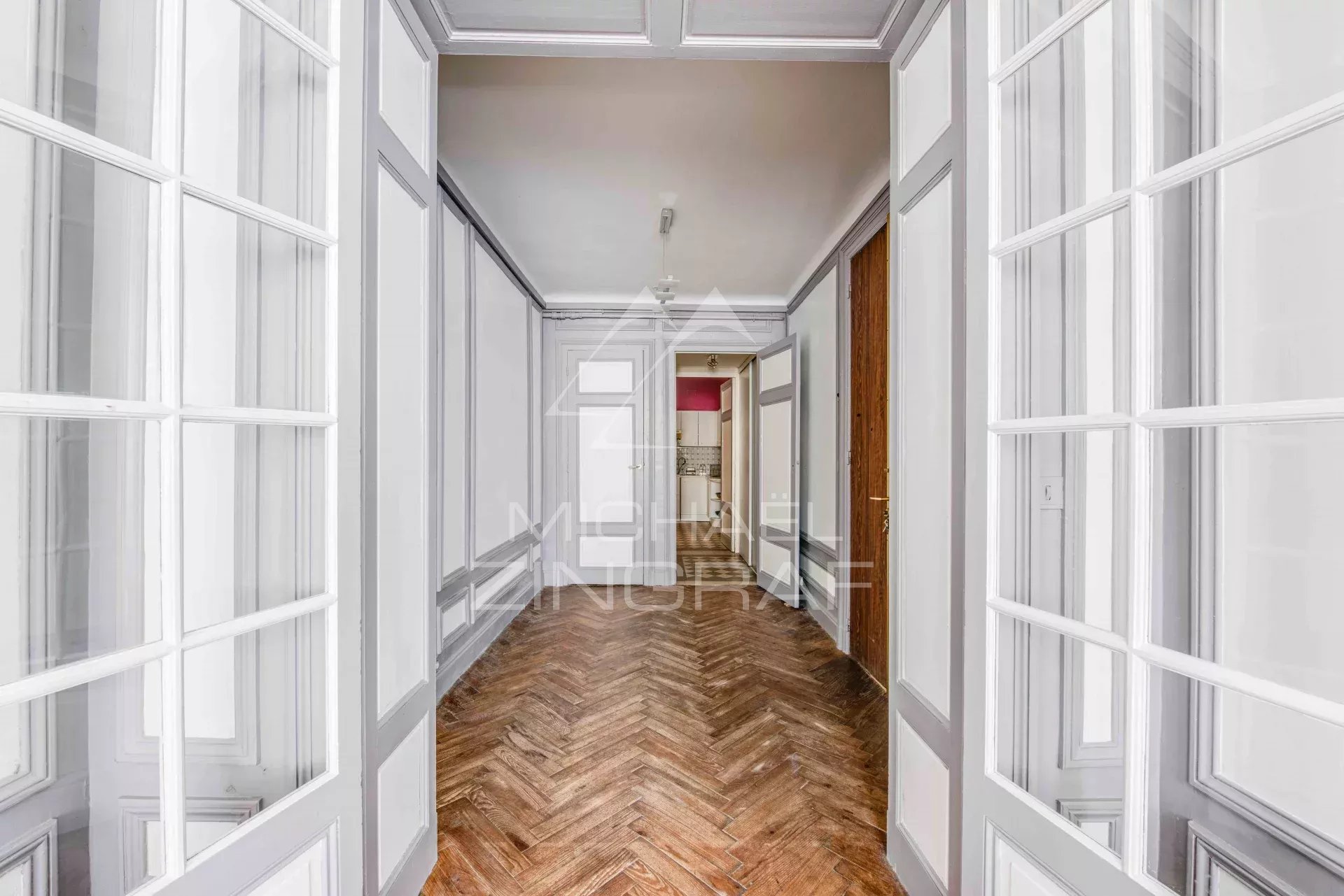 Hall d'entrée d'un appartement spacieux avec parquet et portes vitrées à Biarritz.