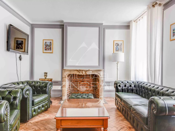 Salon d'un appartement à Biarritz avec canapé en cuir et cheminée en pierre.