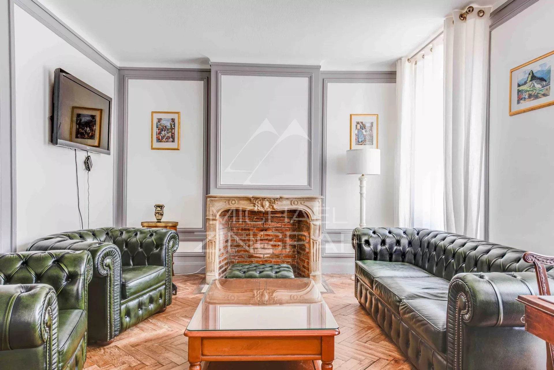Salon d'un appartement à Biarritz avec canapé en cuir et cheminée en pierre.