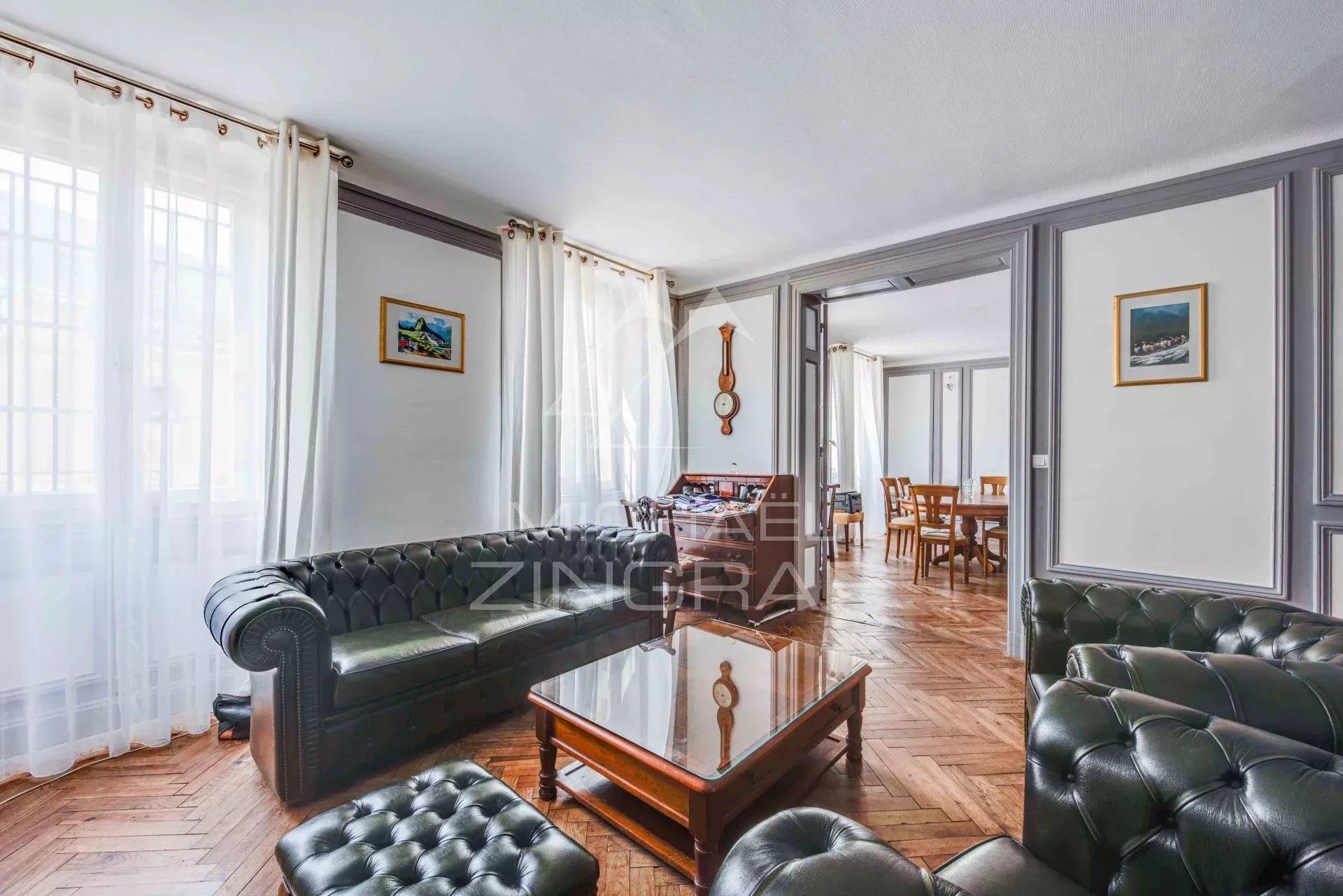 Salon d'un appartement de 105 m2 à Biarritz avec canapé en cuir et cheminée d'époque.