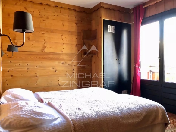 Hotel room with wooden decor, bed and view of the outside in Combloux.