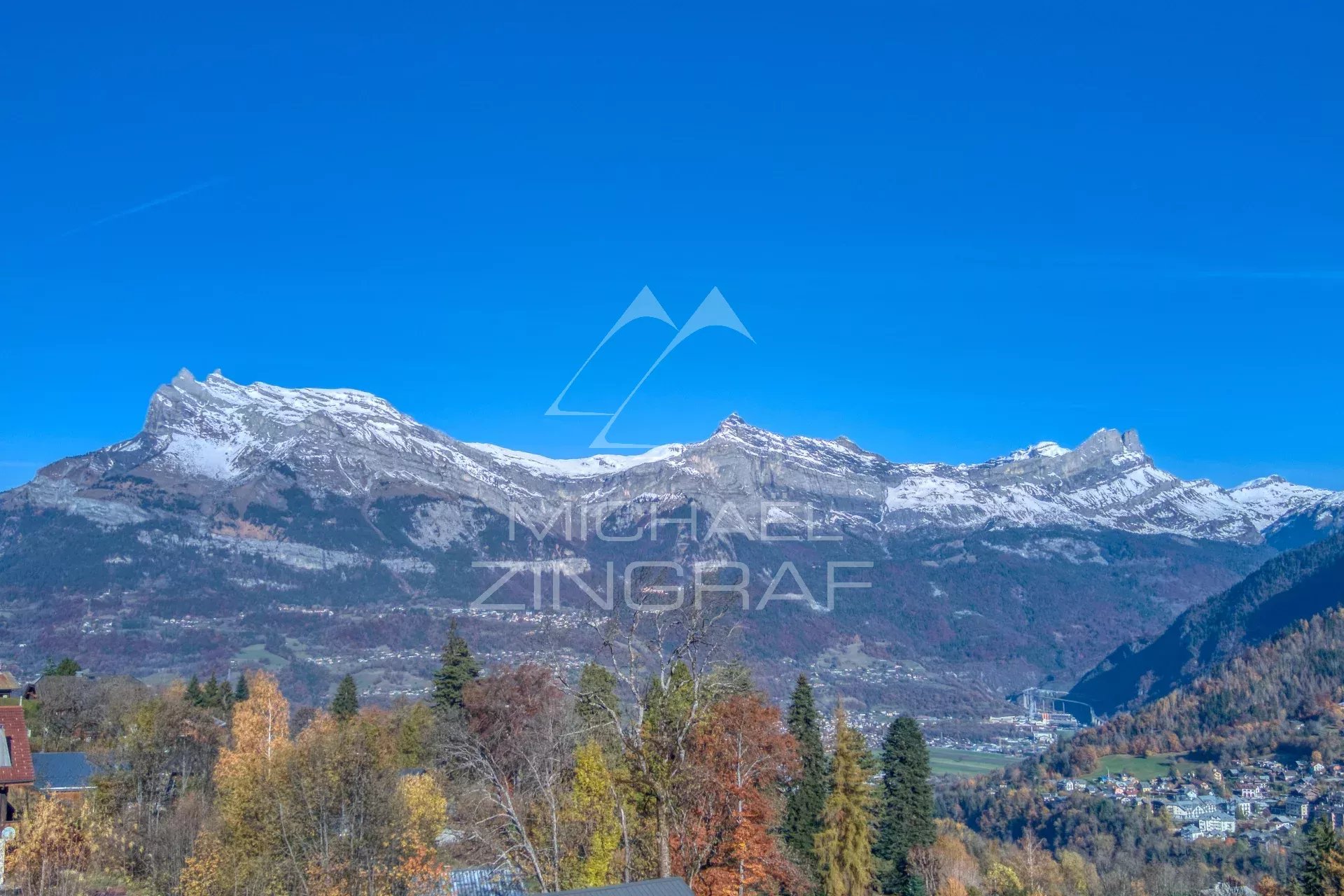 View of the mountains with snow-capped peaks and trees in autumn at Combloux.
