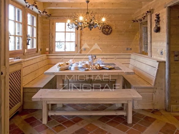Intérieur d'un chalet en bois avec une table en bois et des chaises, décoré de manière rustique.