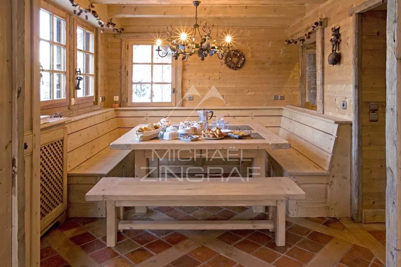 Intérieur d'un chalet en bois avec une table en bois et des chaises, décoré de manière rustique.