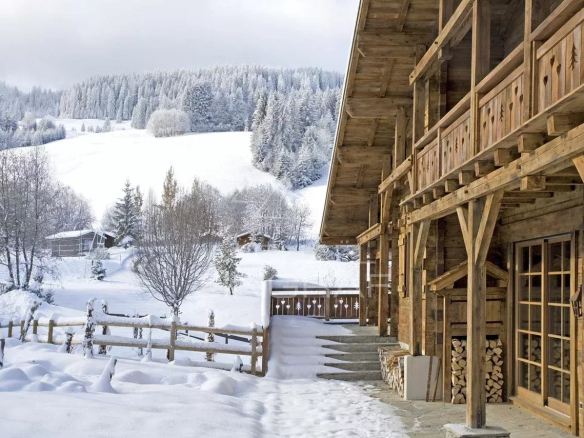 Chalet en bois avec vue sur la montagne et la neige, entouré d'arbres à Megève.