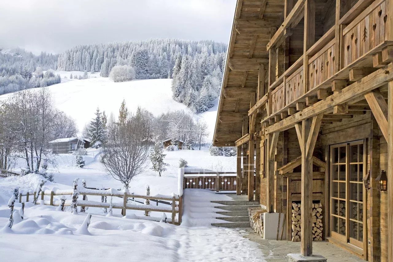 Chalet en bois avec vue sur la montagne et la neige, entouré d'arbres à Megève.