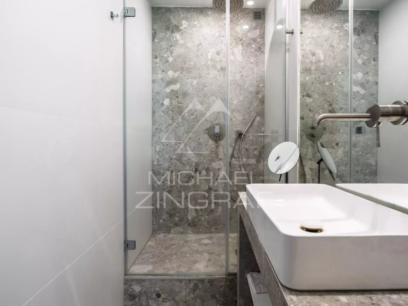 Salle de bain moderne avec douche en verre et lavabo en pierre dans un appartement rénové.