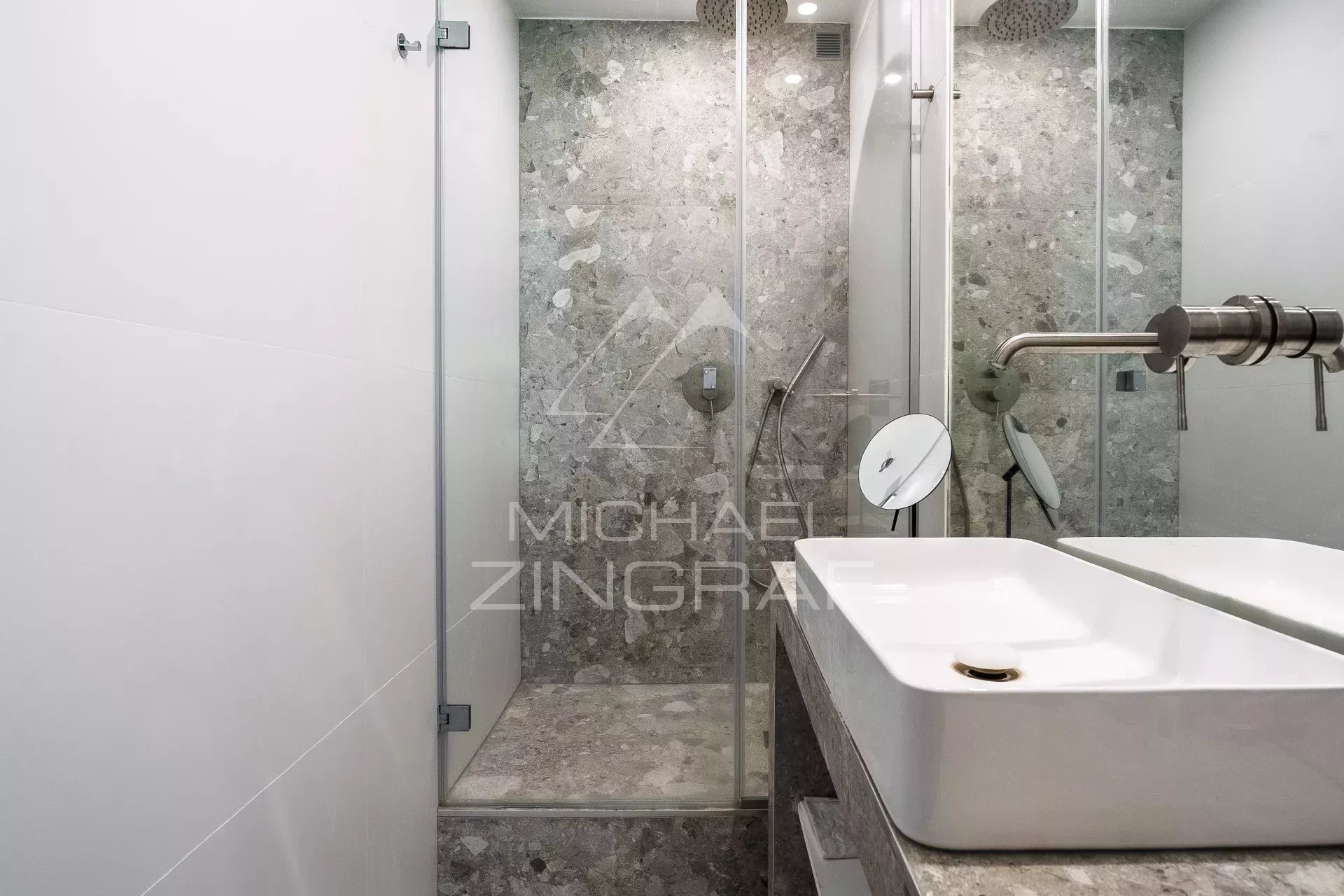 Salle de bain moderne avec douche en verre et lavabo en pierre dans un appartement rénové.