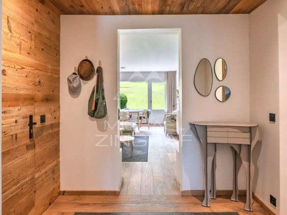 Entrée d'un appartement rénové à Megève avec parquet en bois et décoration moderne.