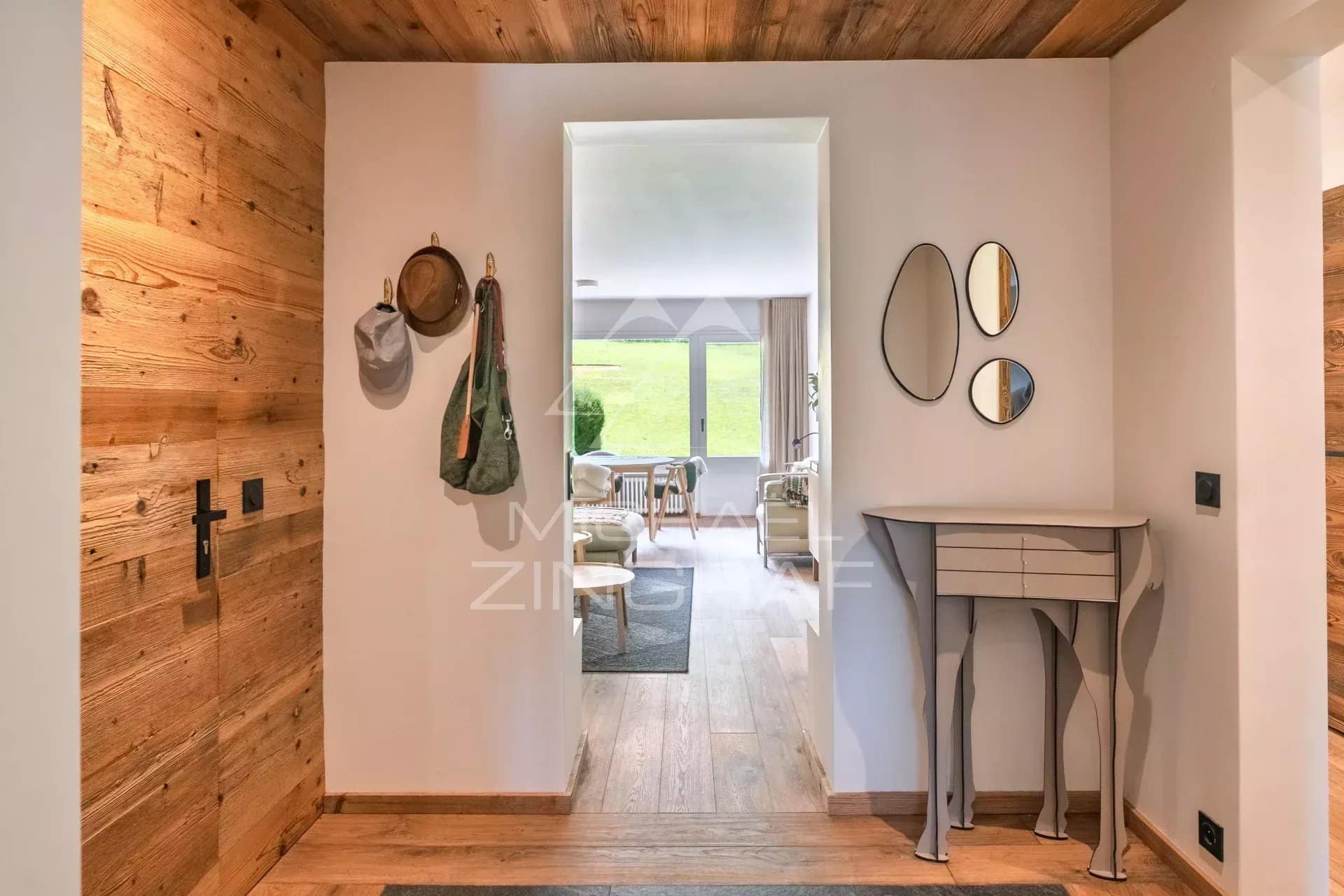 Entrée d'un appartement rénové à Megève avec parquet en bois et décoration moderne.