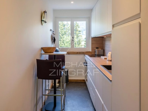 Cuisine moderne et lumineuse d'un appartement rénové à Megève, avec bar et fenêtres.