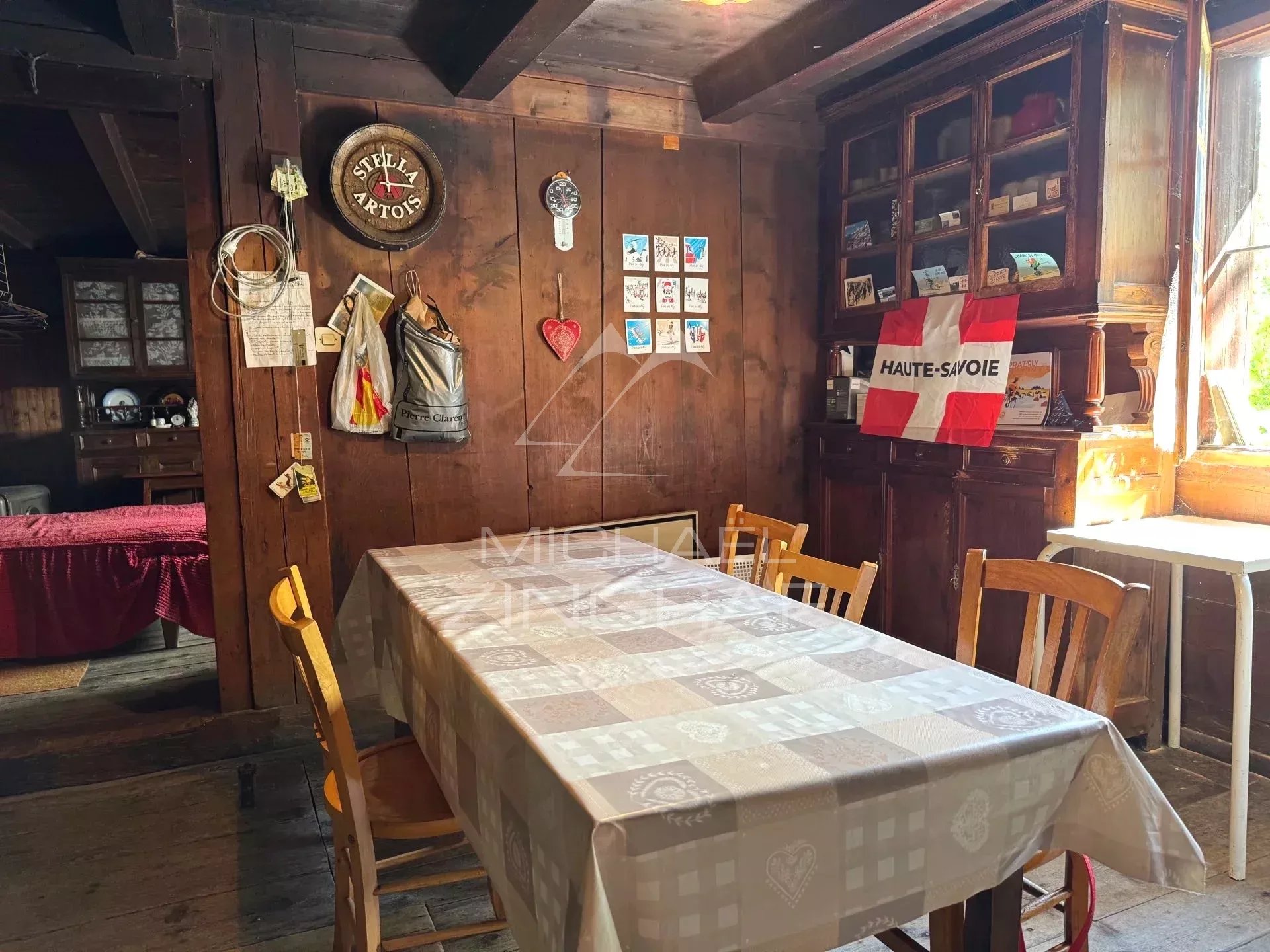 Intérieur d'une petite ferme ancienne à rénover, avec une table et des murs en bois à Praz-sur-Arly.