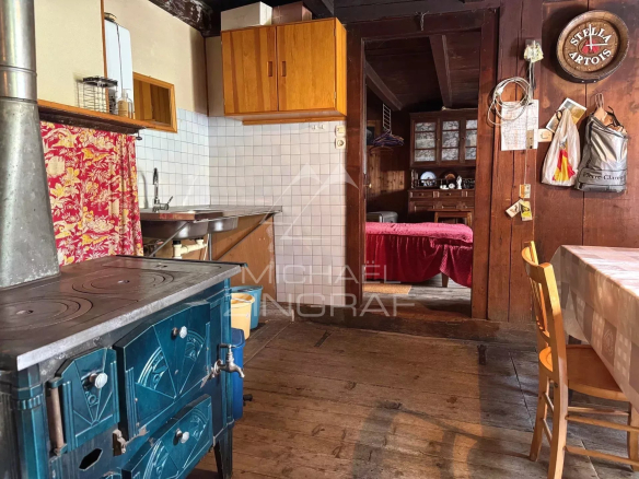Intérieur d'une ancienne ferme à rénover avec une cuisine rustique et un poêle en fonte.