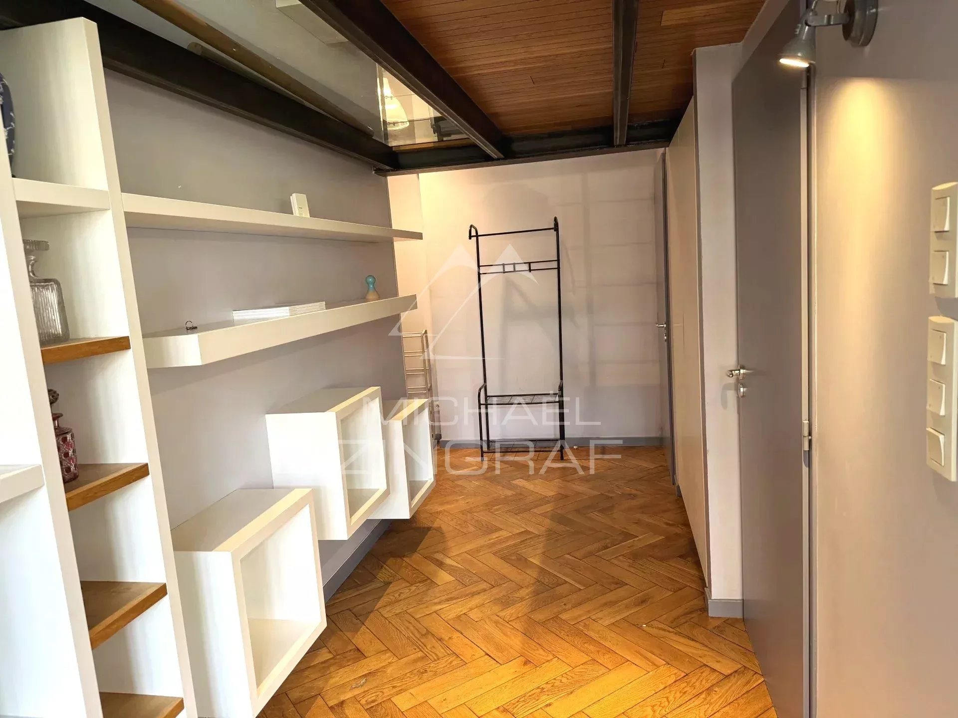 Interior of a renovated loft with shelves and wooden parquet flooring in Lyon 6th arrondissement