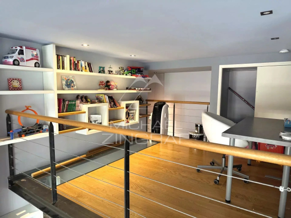 Interior of a renovated loft with mezzanine, office and shelves, bright and spacious.