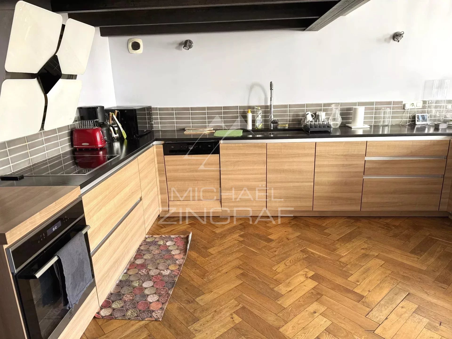 Modern wooden kitchen with black worktop in a renovated loft in Lyon 6th arrondissement.