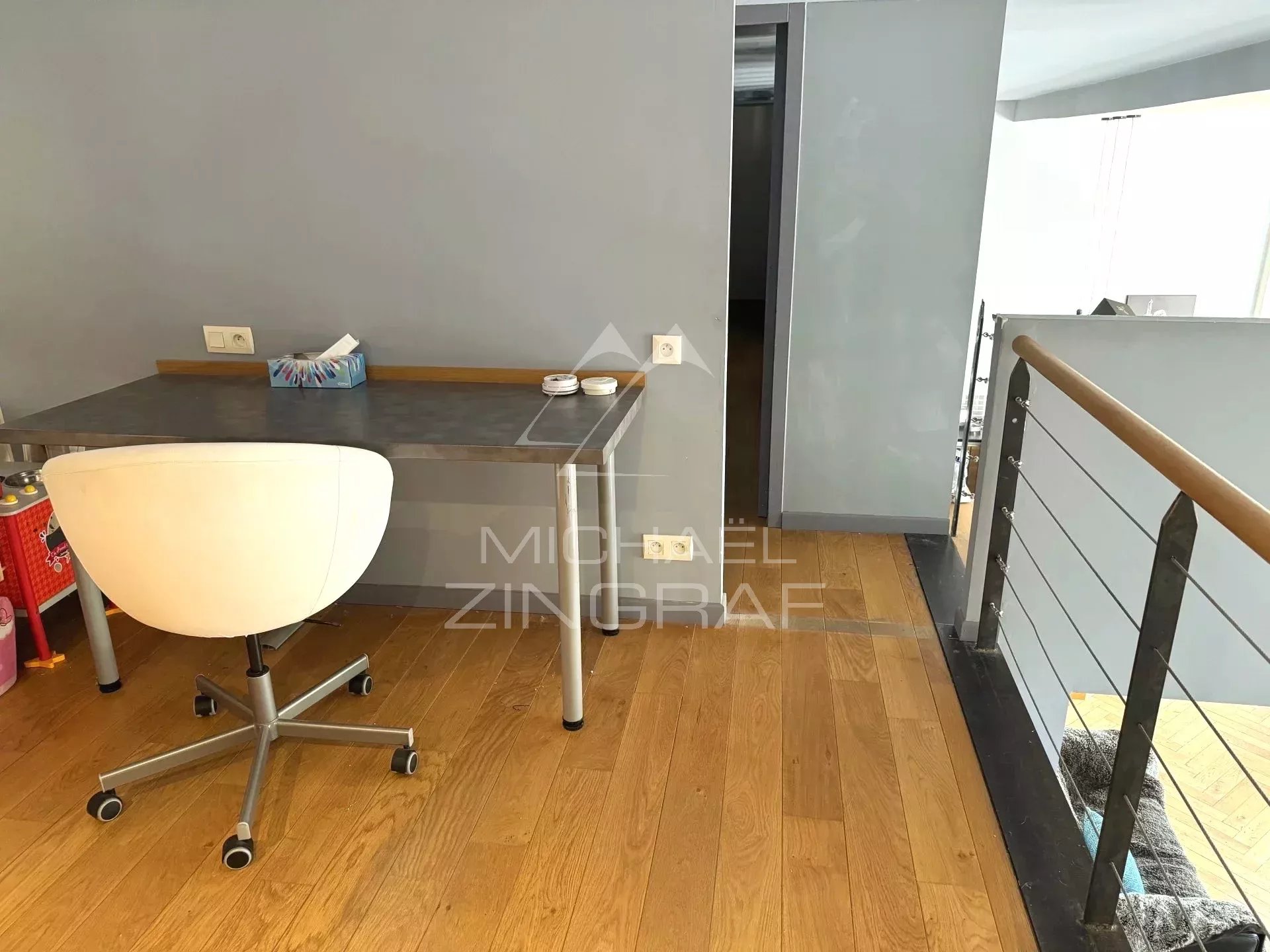 Interior of a renovated loft with an office and wooden floor in Lyon 6th arrondissement.