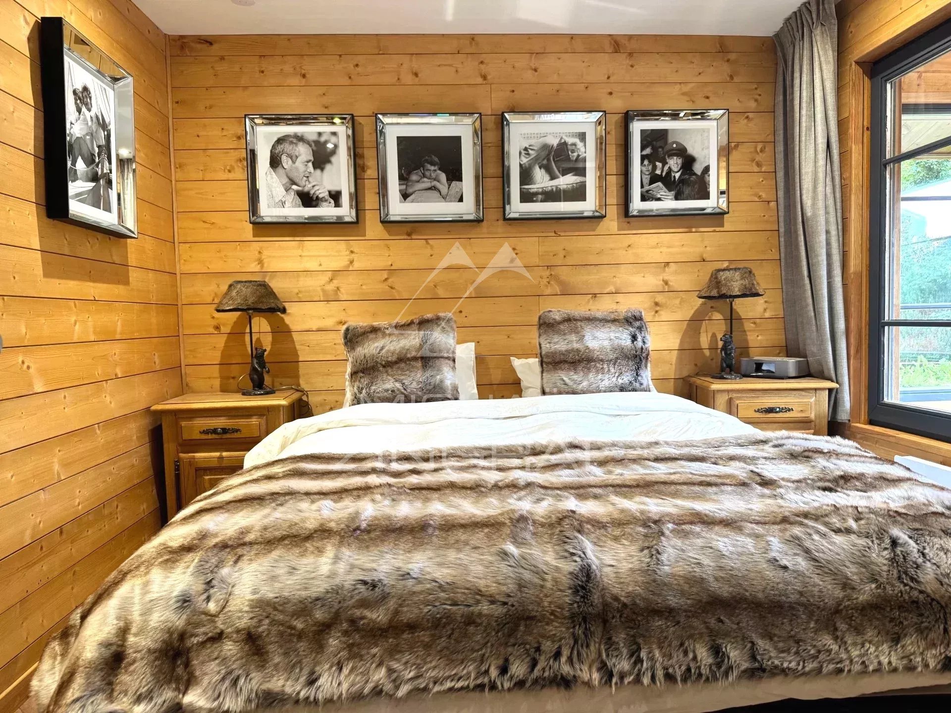 Room in the renovated chalet in Megève Room in a renovated chalet in Megève with wooden walls and a double bed, decorated with black and white photos.