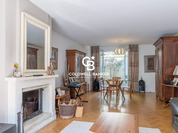 Bright living room with a white fireplace, wooden cabinets, and a round dining table by glass doors to a garden.09