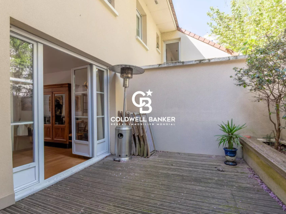 Patio area of a house with open sliding glass doors, a tall outdoor heater, and a stacked wood display on a wooden deck.