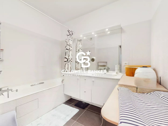 Modern white bathroom with bathtub, vanity and large mirror; Coldwell Banker logo centered over the scene.