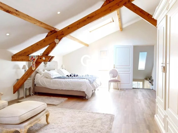 Chambre spacieuse avec poutres apparentes et lit double dans une maison à Suresnes.