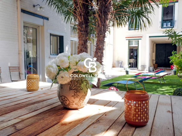Wooden terrace with vase of flowers and lanterns, surrounded by greenery in a house in Suresnes.