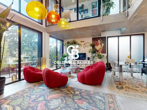 Intérieur d'une maison d'architecte contemporaine à Clamart, avec des fauteuils rouges et des luminaires colorés.