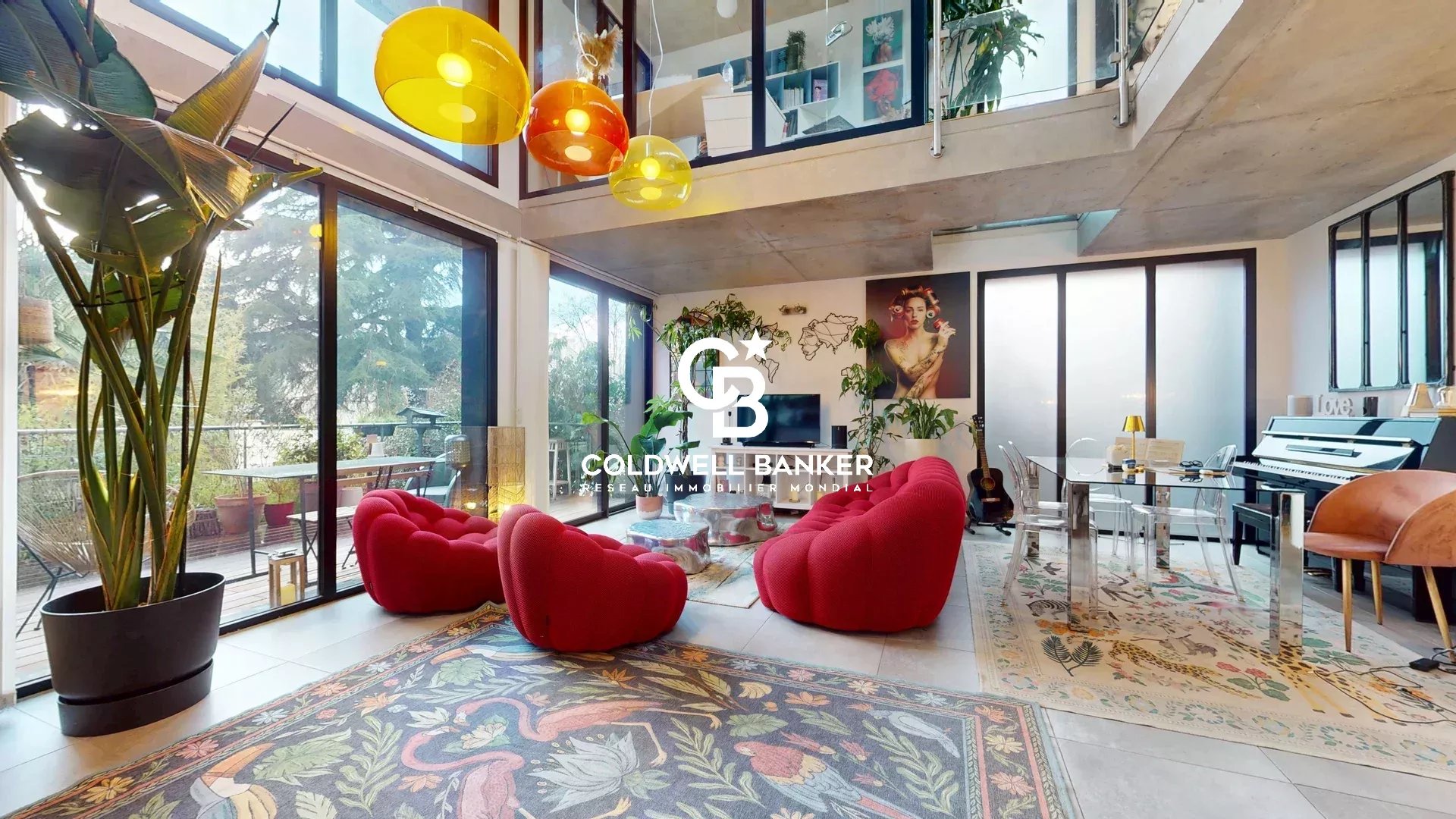 Intérieur d'une maison d'architecte contemporaine à Clamart, avec des fauteuils rouges et des luminaires colorés.