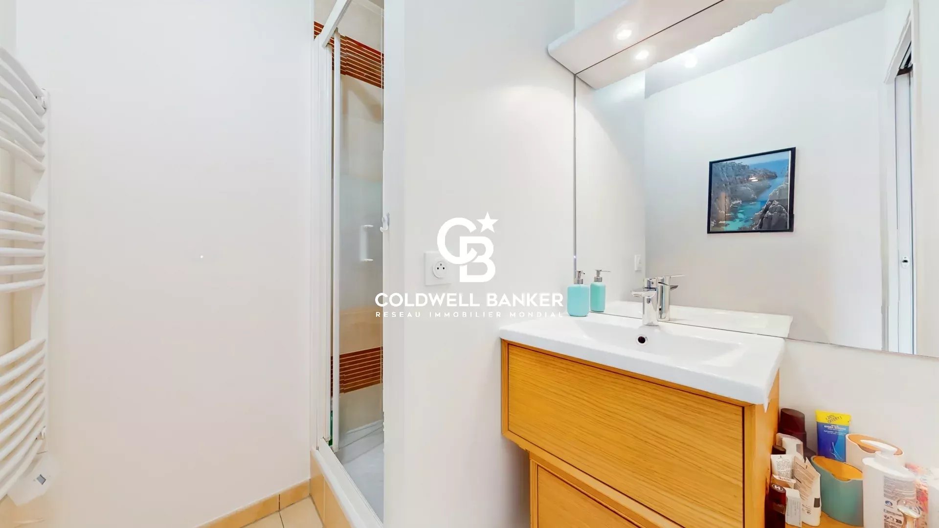 Salle de bain d’un appartement à Montrouge Salle de bain moderne avec douche et meuble en bois clair.